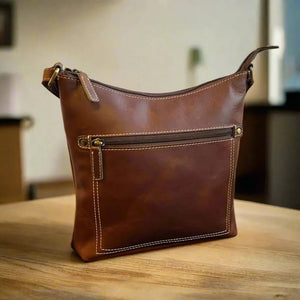 Brown leather handbag on a wooden surface with a blurred indoor background - okotoks hc pharmacy