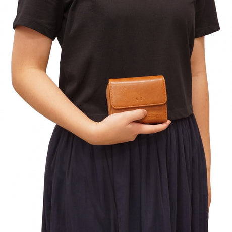 Person holding a brown leather wallet against a black background - okotoks hc pharmacy