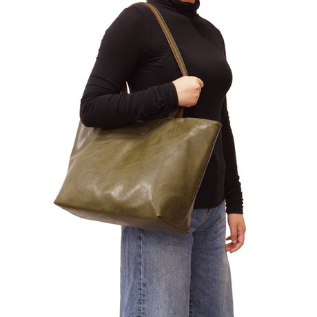 Person holding a green leather tote bag on a white background - okotoks hc pharmacy