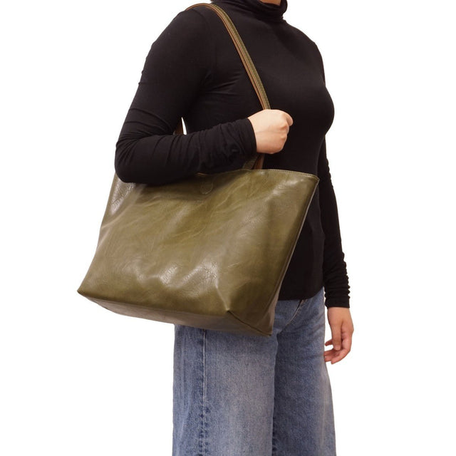 Person holding a green leather tote bag on a white background - okotoks hc pharmacy