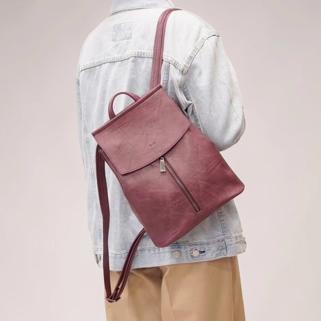 Person wearing a maroon backpack over one shoulder on a plain background - okotoks hc pharmacy