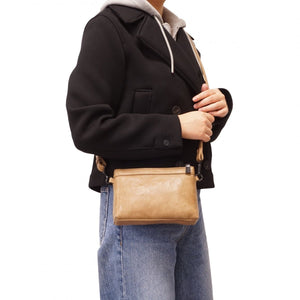 Person wearing a black coat holding a tan leather bag on a white background - okotoks hc pharmacy