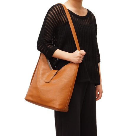 Person holding a brown leather bag against a white background - okotoks hc pharmacy