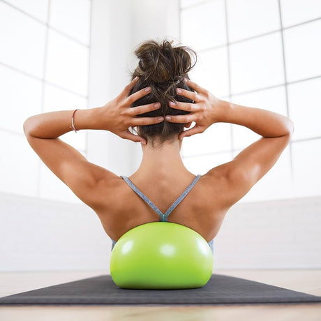 Woman using a green exercise ball for back support on a mat. - okotoks hc pharmacy