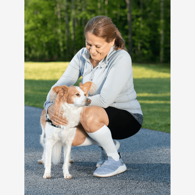 Woman sitting on a path with a dog, surrounded by greenery - okotoks hc pharmacy