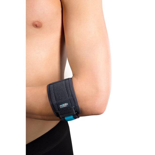 Person wearing a black elbow support brace on a plain background - okotoks hc pharmacy