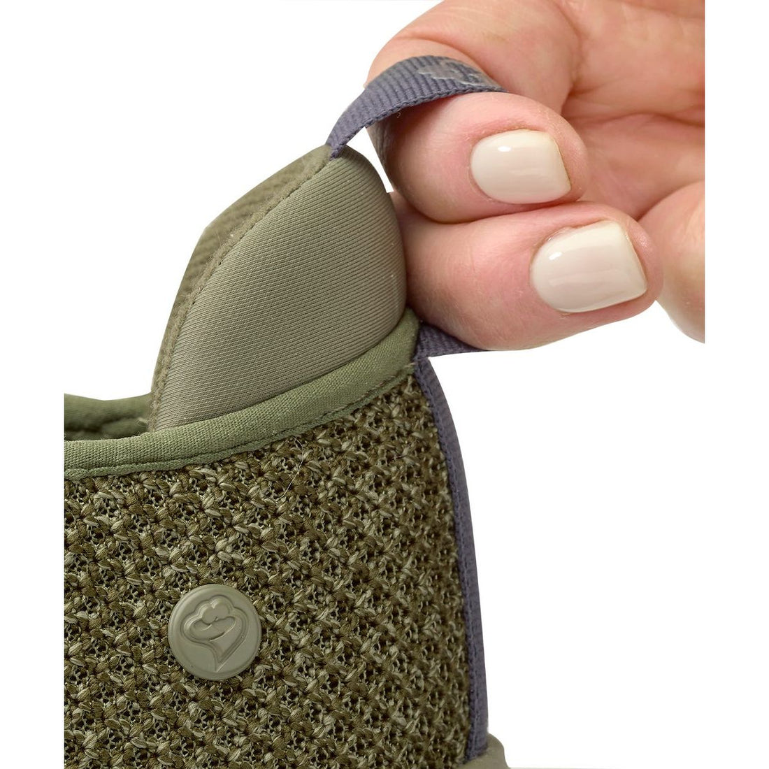 Hand holding a green textured shoe with a brand logo on a white background - okotoks hc pharmacy